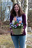 Woman carrying pot with Hyacinthus, Viola cornuta 'Lavender Blush'