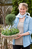 Woman carrying basket bowl with thymus vulgaris (thyme) as stems