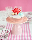 A cupcake decorated with a fondant tea set