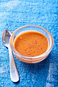Pepper sauce in a glass bowl on a blue background