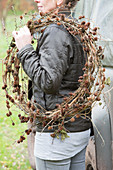 Woman carrying larch branches with cones