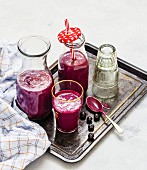 Blueberry smoothies with porridge in bottles and a glass on a tray
