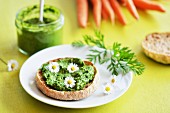 Carrot top pesto spread on bread, decorated with daisies