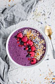 A blueberry smoothie bowl with berries, blossoms, chia and millet seeds