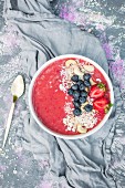 A strawberry smoothie bowl with blueberries, cashew and cereal flakes