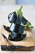 Whole and sliced eggplant on wooden chopping board