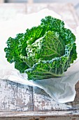 A savoy cabbage on paper and a wooden background