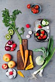 An arrangement of spring onions, garlic, apples, tomatoes, peppers, carrots, kiwi, radishes, strawberries and kohlrabi