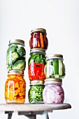 Preserving jars of freshly pickled vegetables stacked on an old stool