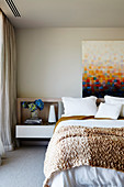Bild mit gemalten Pixeln über dem Bett mit gestrickter Decke