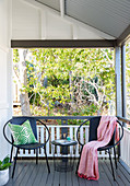 Zwei runde Stühle und ein filigraner Tisch auf der Veranda