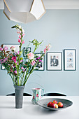 Bouquet in shades of pink on dining table in front of pale blue wall
