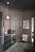 Lilac-grey walls in dark kitchen with black cabinets