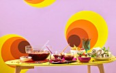 Gedeckter Tisch mit Weinbowle, Guacamole und Wraps für eine Retro-Party