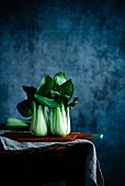 Pak Choi auf Holzbrett vor blauem Hintergrund