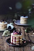 Kleine Chiffon Cakes mit Schwarzkirschen auf rustikalem Holztisch