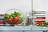 Fresh ripe garden strawberries and melissa herbs in vintage vase standing with empty glass and metal jars