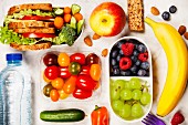 Healthy lunch box with sandwich and fresh vegetables, bottle of water and fruits on wooden background