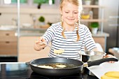 A girl frying banana pancakes in a pan