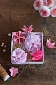 Rosafarbene Origamiblumen und lilafarbene Stoffblumen