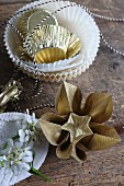 Gold origami flowers next to paper cake cases and bakers' string