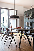 Black, modern dining table in front of hook rails mounted on grey wall