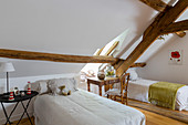 Zwei Einzelbetten im Dachzimmer mit rustikalen Holzbalken
