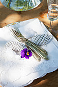 Old silver cutlery and pebbles wrapped in lace on stacked napkins