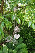 Mobile of chicken wire baskets and wooden heart hung from tree