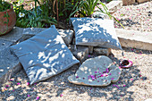 Cushions and leaf-shaped dish on gravel terrace