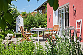 Table and chair on terrace in garden outside deep pink house