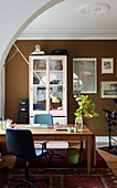 Schreibtisch im Arbeitszimmer mit brauner Wand und Stuckdecke