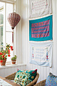 Wall hangings with lettering above rattan armchairs in conservatory