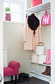 Damenmantel, Hutschachtel und rosa Accessoire in weißer Garderobe