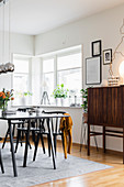 Dining table and chairs next to window and tall retro sideboard against wall