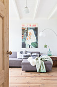 Poster-sized print of magazine cover on wall above grey sofa