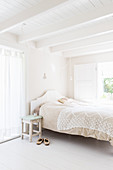 Lacy blanket on bed in bright bedroom decorated entirely in white