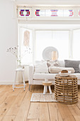 White sofa, standard lamp and wicker coffee table in front of window bay