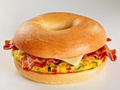 A bagel with omelette, bacon and cheese