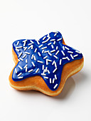 A star-shaped doughnut with blue glazing and white hundreds and thousands