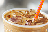 Iced coffee in a plastic cup with a straw (close-up)
