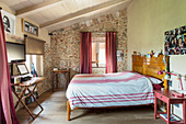 Red accents and stone wall in Mediterranean bedroom