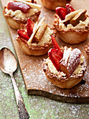 Rhubarb, strawberry and coconut tartlets on a wooden board