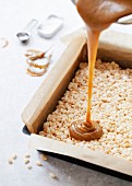 Pouring Caramel over Rice Krispie Marshmallow Treat Base