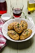 Hasselback potatoes with olive oil and thyme, served with a glass of red wine