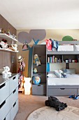 Loft bed with drawers below against mural on wall in child's bedroom