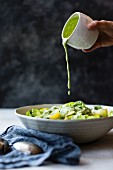Gemüsesalat wird mit veganem Kräuter-Cashew-Dressing beträufelt