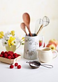 Fresh raspberries, icing sugar and kitchen utensils on a table