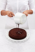 Chef pours the chocolate glaze over the top of a cake