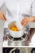 Chef removes baking paper from a suace pan filled with orange slices